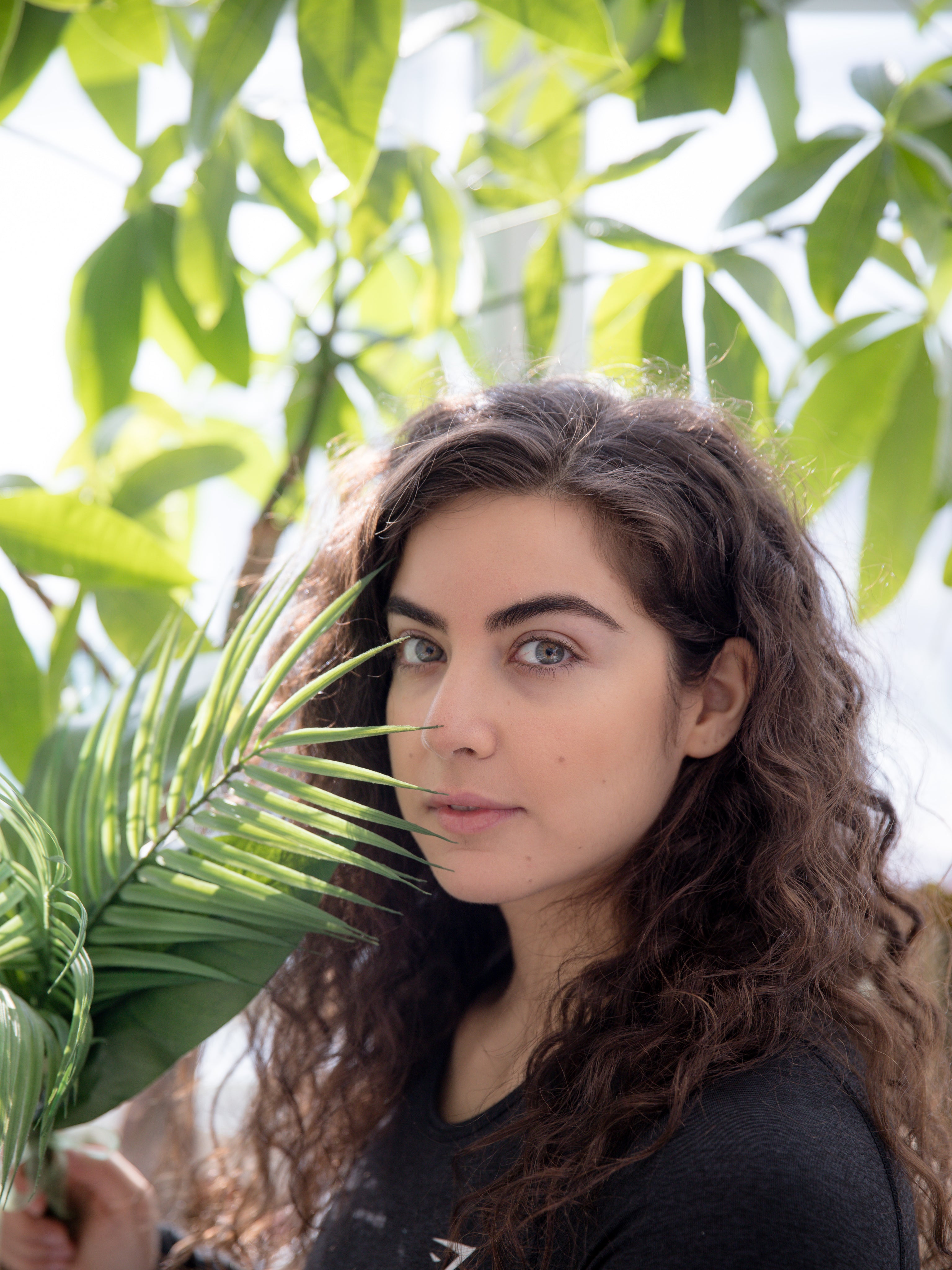 files/person-with-long-curly-hair-surrounded-by-green-leaves.jpg